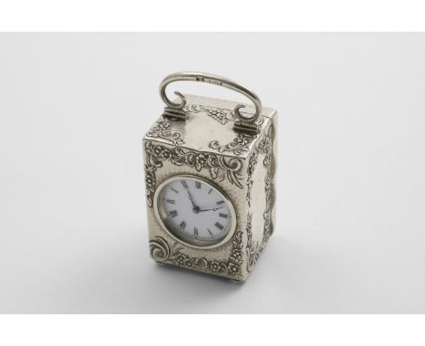 A LATE VICTORIAN CARRIAGE TIMEPIECE  on button feet with a swing handle and chased and hammered decoration on the case, the w