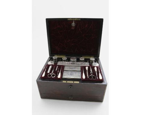 A VICTORIAN BRASS BOUND ROSEWOOD TOILET BOX fitted with 10 mounted glass bottles/boxes with engraved decoration and a mother 