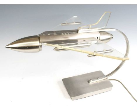 A contemporary brushed aluminium and perspex table lamp in the form of a jet plane, on curved support to integral plain recta