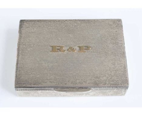 A 1980s silver pocket cigarette case, having engine turned exterior, with applied yellow metal monogram R&amp;P to cover (Roe