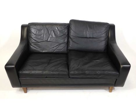 A 1960s Danish black leather two-seater sofa, having squab back and seat cushions, raised on teak square tapering supports, w