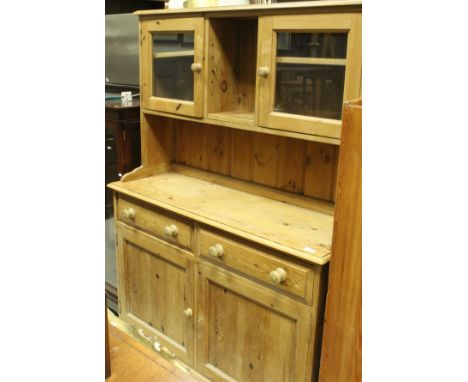 A modern pine dresser of small proportions, the top with two glazed cabinets flanking a single shelf above a plain top to two