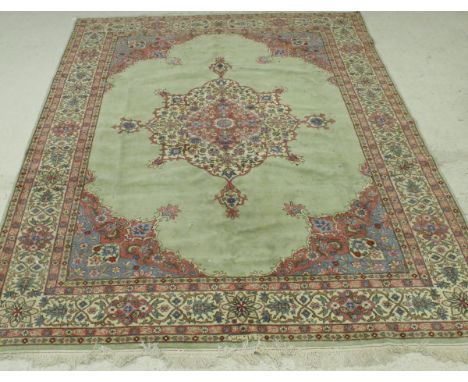 A Persian carpet, the central panel set with a stylised flower head medallion on a pale green ground within a stepped green a