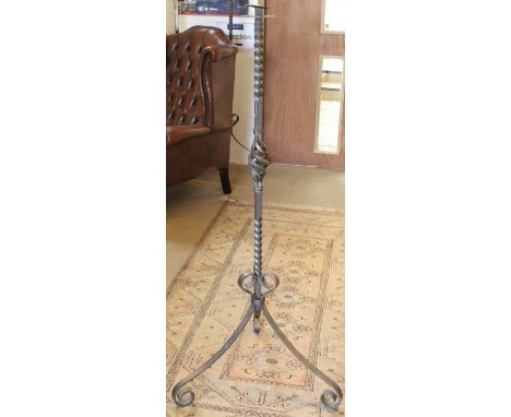 A pair of 20th century wrought iron floor standing candle holders on scrolling tripod supports