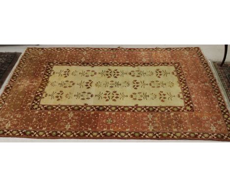 A modern Agra carpet, the cream central panel decorated with floral sprays, within a pale red and darker red floral decorated