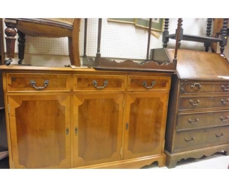 A 20th Century yew sideboard of three drawers above three cupboard doors with a shaped apron, raised on bracket feet, a 20th 
