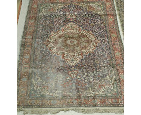 A Persian carpet, the central panel set with stylised flower head medallion on a mauve floral decorated ground within a stepp