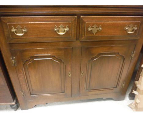 A modern oak side cabinet, the plain top above two drawers with brass handles and two cupboard doors to bracket feet, togethe