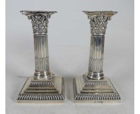 A pair of Edwardian silver table candlesticks, each having a removable sconce on a Corinthian column and stepped square weigh