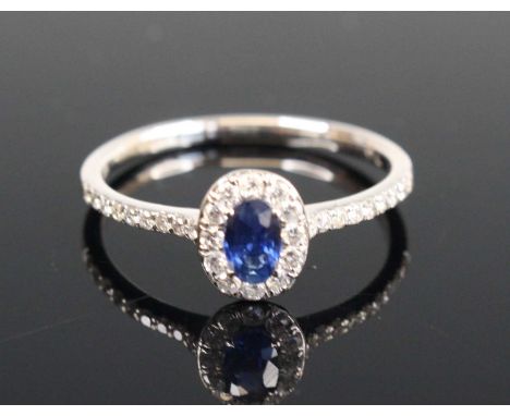 A contemporary 18ct gold sapphire and diamond ring, arranged as a central oval cut sapphire measuring approx 5.1 x 3.2mm, in 