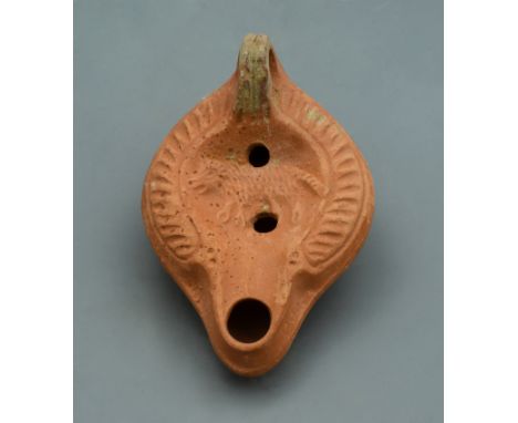 A red burnished terracotta oil lamp with central design in the form of a wolf; perhaps a legend of Romulus and Remus. - 120mm