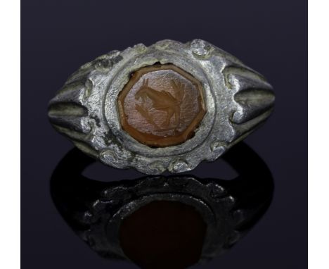 A Roman Carnelian intaglio ring with peacock; composing a large D-shaped band with elaborately decorated shoulders. The peaco