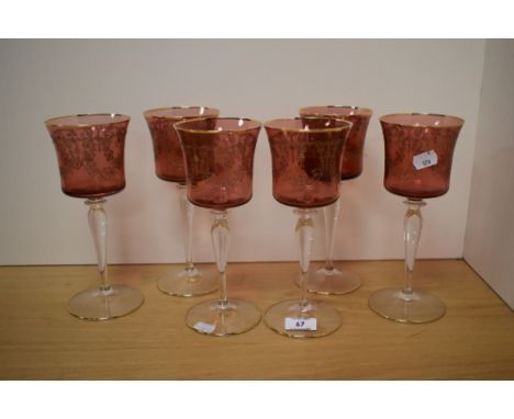 A set of six 20th Century Bohemian ruby coloured glass wine glasses, having gilt etched foliate design and measuring 23cm hig