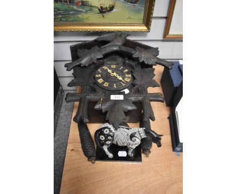 An early 20th Century Black Forest cuckoo clock, heavily carved and surmounted by a bird and flowers above the cuckoo and doo