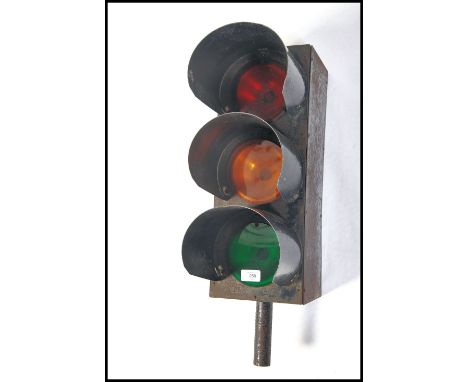 A vintage early 20th century traffic light having ebonised metal construction with hoods to each light and coloured facias to