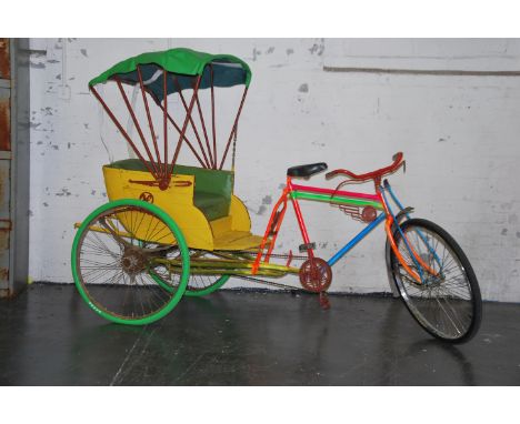 A vintage asian full size rickshaw bicycle having wonderful colours having air in the tyres, green tyres to the back, the yel