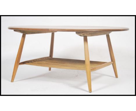 A 1970's original Ercol beech and elm wood circular coffee table. Raised on tapering beech wood legs united by a spindle gall