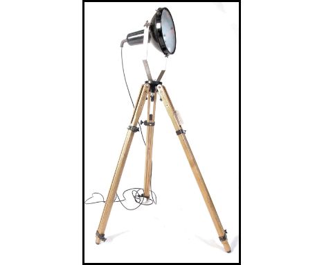 A mid 20th century vintage industrial up-cycled spot light. The floor lamp being raised on a vintage wooden metamorphic tripo