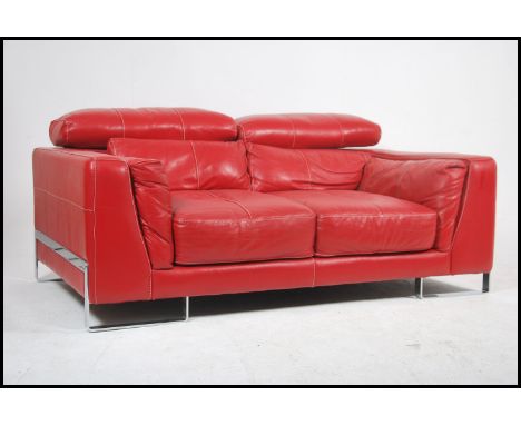 A contemporary red leather Italian sofa raised on strap chrome work legs and exterior frame, the deep sofa with re red stitch