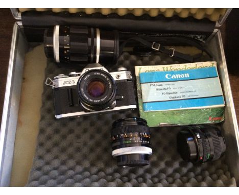 A padded suitcase of Canon camera equipment including an AE-1 camera body, various lenses (28mm, 50mm) and instructions.