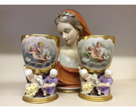 A pair of decorative goblets with attached figurines on the base, and a ceramic bust of a Neo-Classical Roman noblewoman.