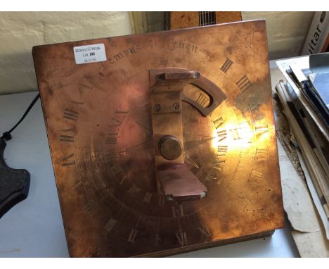 A copper sundial on wooden base.