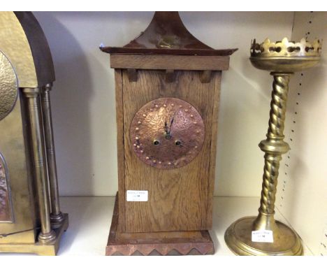 An Arts and Crafts style mantle clock with copper face on wooden base.