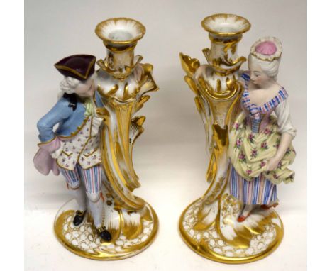 Pair of late 19th century Paris porcelain candlesticks, richly gilded, flanked by a lady and gent in 18th century costume, de