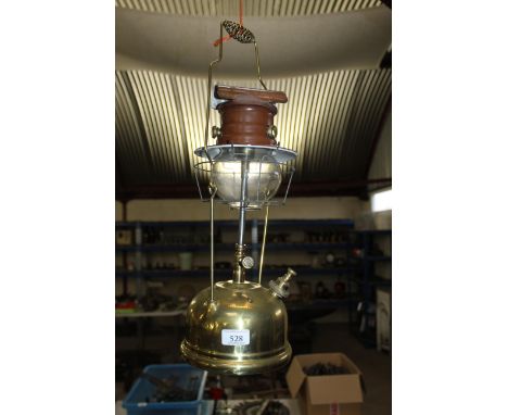 A Tilley storm lantern with brass reservoir, brown metal cowled top and Tilley glass shade