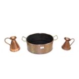 A copper twin handle oval shaped cooking pot and two small copper jugs