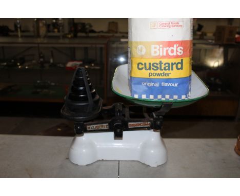 A set of white enamel Avery scales with enamelled pan and set of weights with ornamental custard powder bag