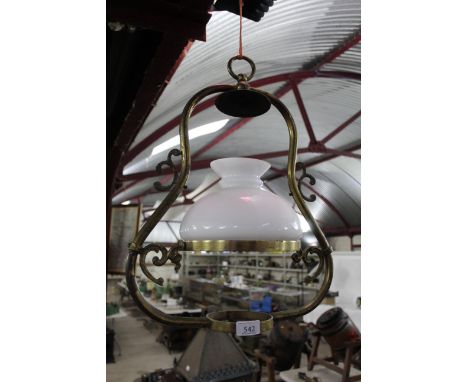 A brass hanging oil lamp frame with ornate pattern and opaque glass shade