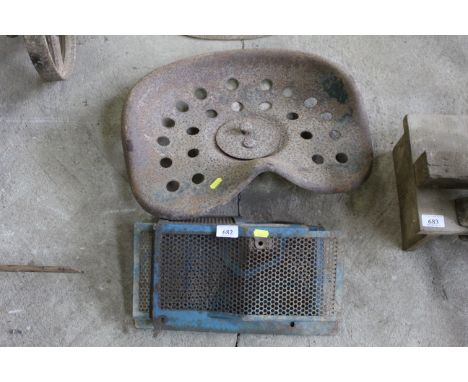 A vintage metal tractor seat and a Ford 4000 fan belt guard