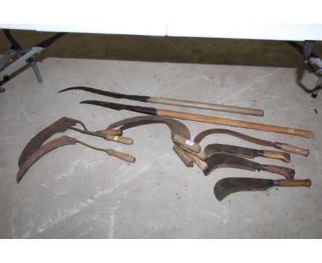 A quantity of wooden handled tools to include sickles, bill hooks, long handled slashers etc.