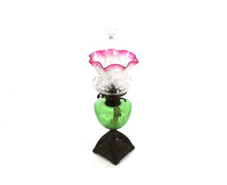An ornate Victorian oil lamp with brass base, green reservoir and ornate shade with cranberry glass top and chimney