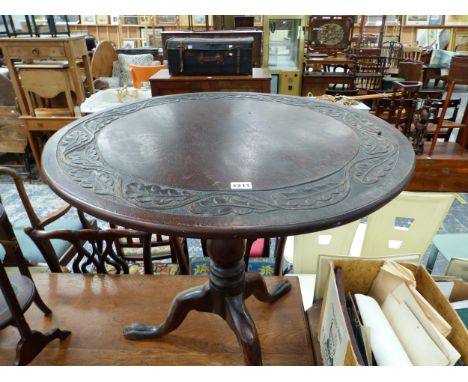 AN OAK TRIPOD TABLE WITH A LEAF BAND CARVED INTO THE CIRCULAR TOP