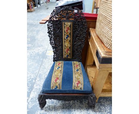 AN ANGLO-INDIAN PIERCED AND CARVED HARD WOOD CHAIR WITH NEEDLEWORK PANEL CENTRAL TO THE BACK AND COVERING THE DROP IN SEAT