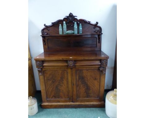 A VICTORIAN MAHOGANY TWO DOOR SIDE CABINET, THE FOLIATE CARVED BACK WITH SERPENTINE FRONTED SHELF.   W 120 x D 52 x H 178cms.