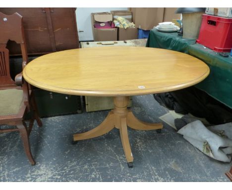 AN OAK OVAL TOPPED TABLE ON BALUSTER COLUMN AND FOUR LEGS WITH MODERN CASTOR FEET