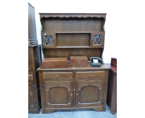 AN OAK DRESSER WITH A SHELF CENTRAL TO THE ENCLOSED BACK FLANKED BY LEADED GLASS DOORED PIGEON HOLES.   W 122  x D 43 x H 177