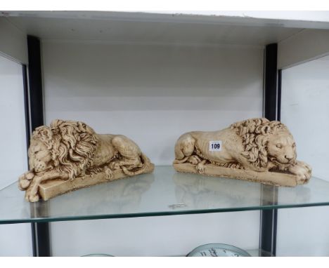 A PAIR OF CAST CERAMIC RECLINING LIONS