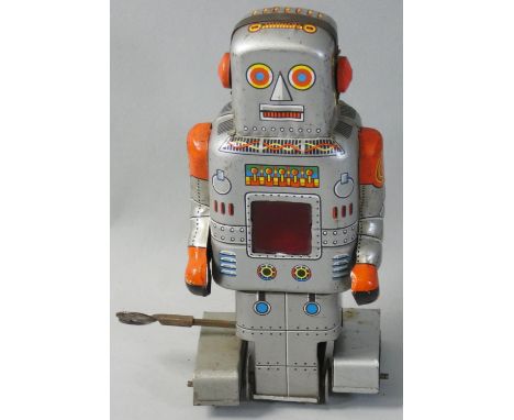 A wind-up tin clockwork walking robot, made in Japan by S.Y. Co., circa 1950?s, with red sparkling panel to the front, height