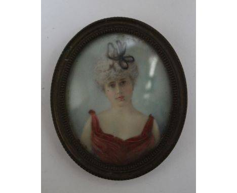 A LATE 19TH / EARLY 20TH CENTURY PORTRAIT MINIATURE OF A LADY IN A RED DRESS, in an oval metal frame, unsigned, framed and gl