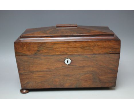 A 19TH CENTURY ROSEWOOD SARCOPHAGUS SHAPED TEA CADDY, the hinged lid opening to a part fitted interior, raised on squat bun f