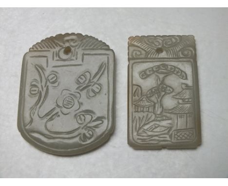 TWO CHINESE CELADON CARVED JADE PENDANTS, finely carved in shallow relief one with flower and foliate decoration, the smaller