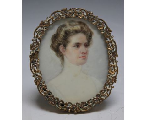 A LATE 19TH / EARLY 20TH CENTURY OVAL PORTRAIT MINIATURE OF A YOUNG WOMAN, in an oval decorative gilt metal frame with strut 