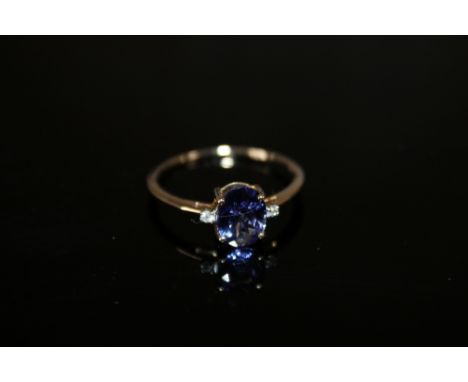 A HALLMARKED 9 CARAT GOLD TANZANITE RING, the oval tanzanite coming with a stone either side, and is approx 1.71 carats, meas