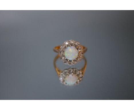 A HALLMARKED 18 CARAT GOLD OPAL AND DIAMOND RING, the circular domed opal is approx 7 mm Dia and is surrounded by twelve smal