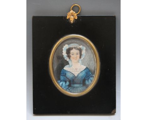A LATE 19TH / EARLY 20TH CENTURY OVAL PORTRAIT MINIATURE OF A YOUNG LADY IN A BLUE DRESS AND BONNET, in black frame with acor