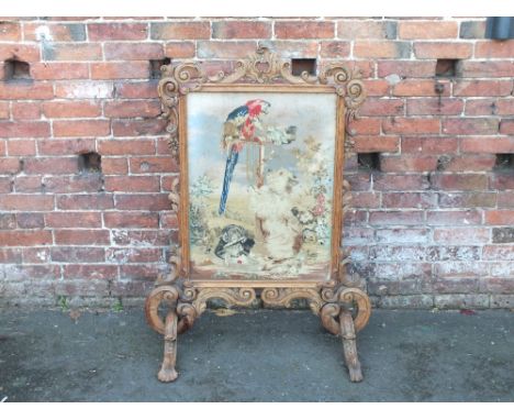 A LARGE VICTORIAN STRIPPED OAK FIRESCREEN, the frame with carved, pierced and scrolling detail, the glazed inset needlepoint 